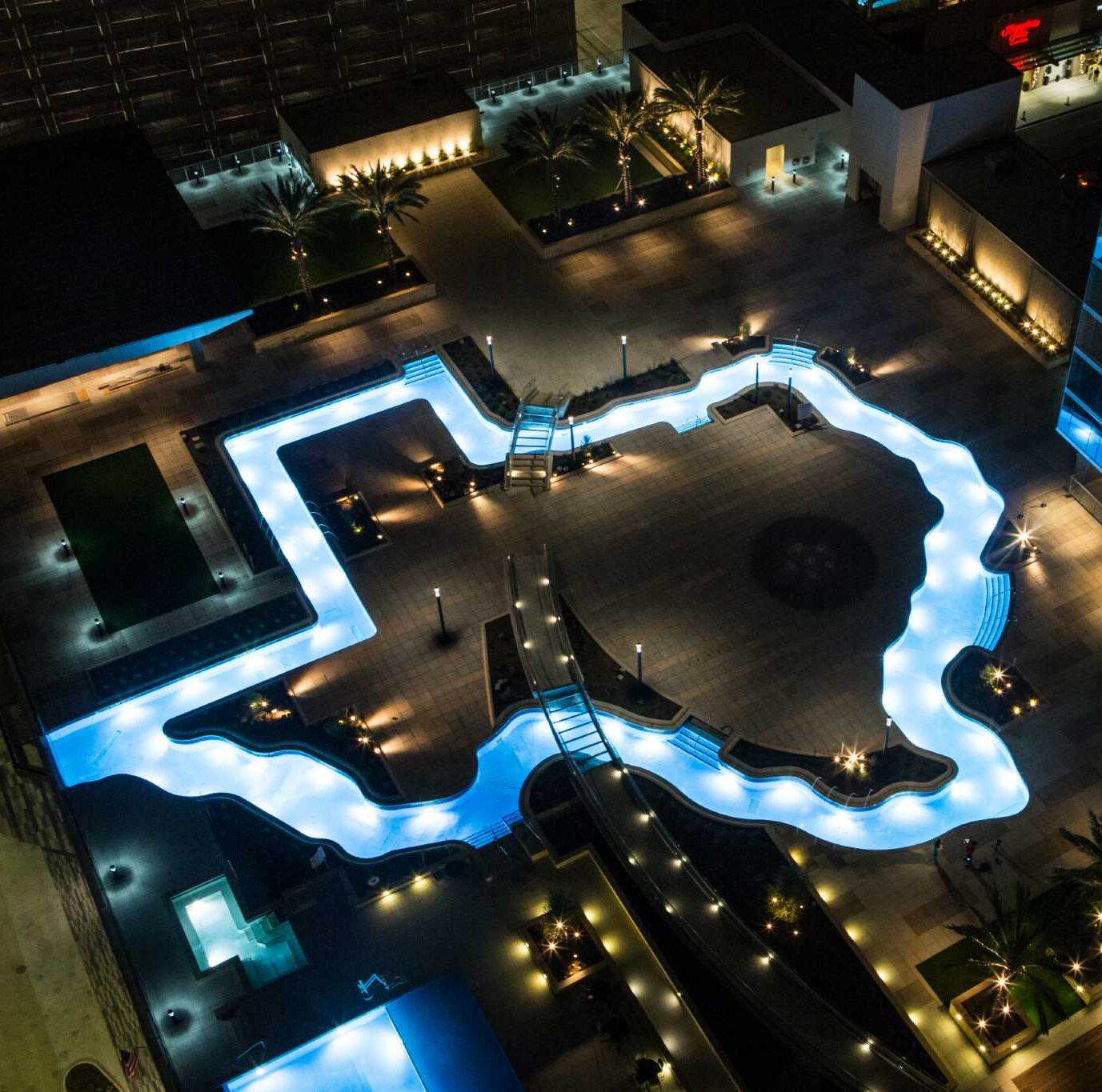 stainless steel lazy river in the shape of Texas lit up at night
